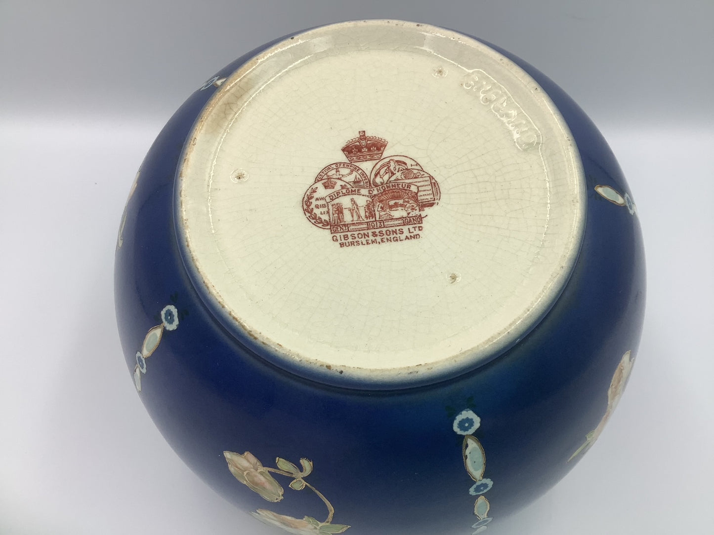 This lovely navy vase with pink/peach floral design circled in gold, and topped by a brass flower frog was made by Gibson & Sons in Burslem England between 1930 and 1950.