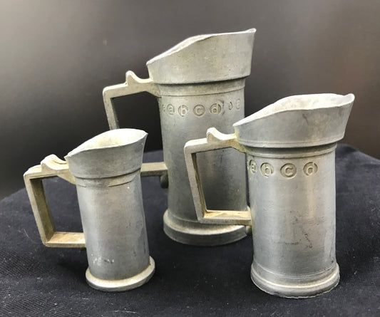 A lovely set of three vintage pewter measuring pitchers.